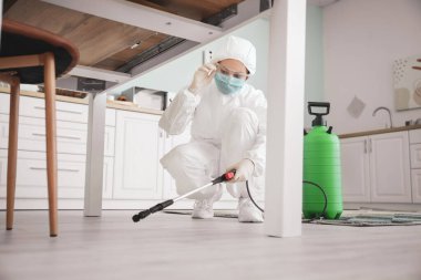 Biyolojik tehlike giysisi giyen bir işçi evi dezenfekte ediyor.