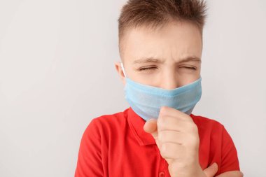Gri arka planda koruyucu maske takan küçük bir çocuk. Salgın kavramı