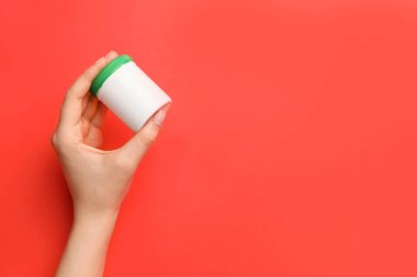 Arka planda ilaç şişesi olan bir kadın eli.