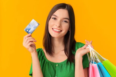 Güzel genç kadın alışveriş torbaları ve renk arka plan üzerinde kredi kartı ile