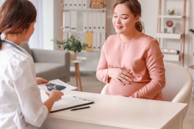Genç hamile kadın klinikteki doktoru ziyaret ediyor.