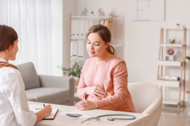 Genç hamile kadın klinikteki doktoru ziyaret ediyor.