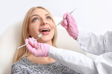 Diş teli takan genç bir kadın kliniğe gidiyor.