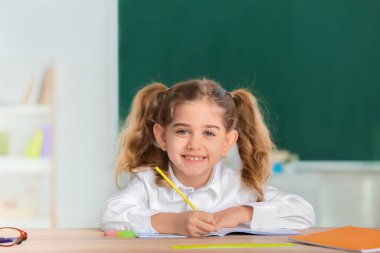 Sınıftaki küçük tatlı kız öğrenci masasında.
