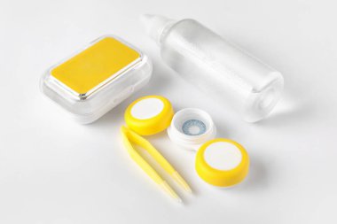 Kontak lensleri, solüsyonu ve beyaz arkaplanda cımbızı olan kaplar