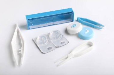 Beyaz arkaplanda kontak lensler ve cımbızlar için kaplar