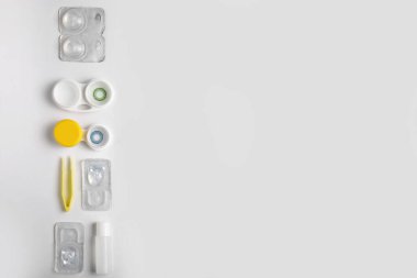 Kontak lensleri, solüsyonu ve beyaz arkaplanda cımbızı olan kaplar