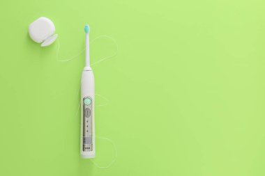 Arka planda diş ipiyle elektrikli diş fırçası