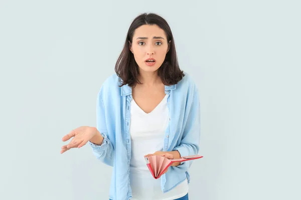 Mujer Joven Preocupada Con Cartera Vacía Sobre Fondo Claro —  Fotos de Stock