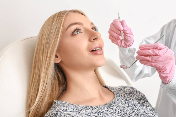 Young woman with dental braces visiting orthodontist in clinic