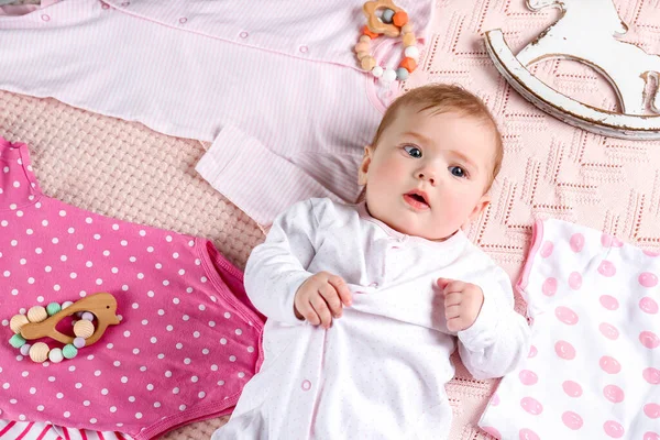 Söt Baby Med Olika Stilrena Kläder Och Leksaker Liggande Sängen — Stockfoto