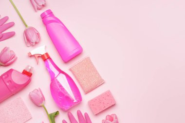 Renkli arkaplanda temizlik malzemeleri ve bahar çiçekleri.