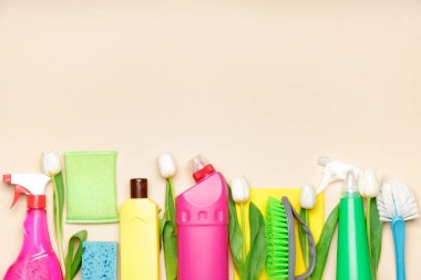 Renkli arkaplanda temizlik malzemeleri ve bahar çiçekleri.