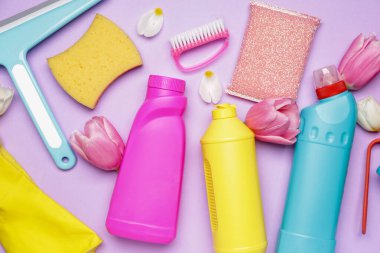 Renkli arkaplanda temizlik malzemeleri ve bahar çiçekleri.