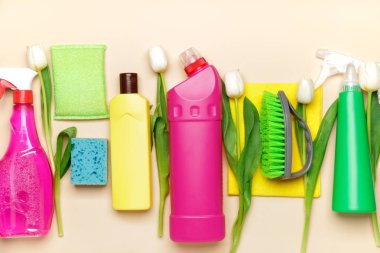 Renkli arkaplanda temizlik malzemeleri ve bahar çiçekleri.