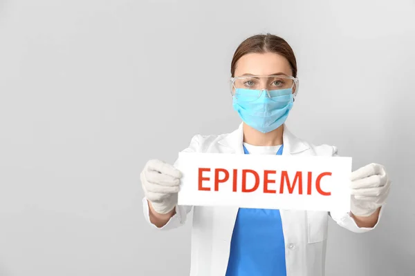 灰色の背景にテキストEpidemicと保護マスク保持紙シートの医師 — ストック写真