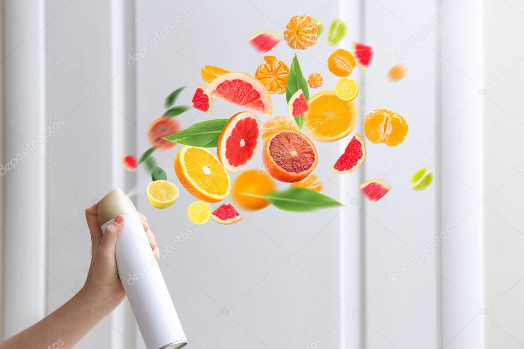 Woman spraying citrus air freshener at home