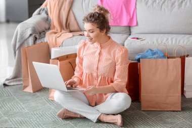 Güzel genç bayan evde online alışveriş için dizüstü bilgisayar kullanıyor.
