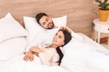 Mutlu genç çift evde yatakta yatıyor.