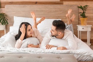 Mutlu genç çift evde yatakta yatıyor.