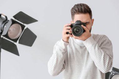 Stüdyoda kameralı bir erkek fotoğrafçı.