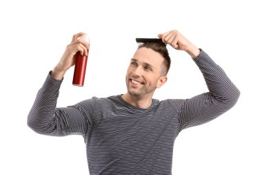 Beyaz arka planda saç spreyi olan yakışıklı bir genç.