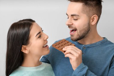 Hafif arka planda lezzetli çikolataları olan güzel genç bir çift.