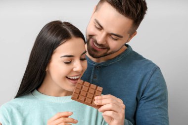 Hafif arka planda lezzetli çikolataları olan güzel genç bir çift.