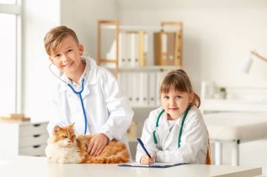 Klinikte şirin kedileri muayene eden küçük veterinerler.