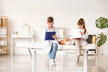 Klinikte şirin kedileri muayene eden küçük veterinerler.