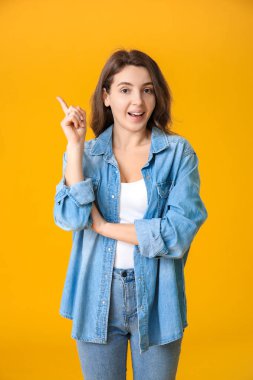 Renkli arka planda işaret parmağı olan güzel bir genç kız.