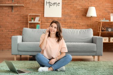Güzel genç kız evde telefonla konuşuyor.
