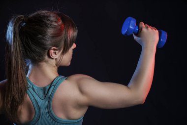 Koyu arka plan üzerinde dumbbells ile sportif kaslı kadın