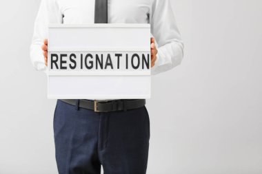 Işık arkaplan üzerinde metin RESIGNation ile pano tutan adam