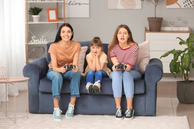 Evlatlık kızla evde video oyunu oynayan mutlu lezbiyen çift.