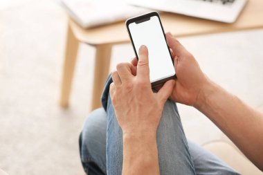 Evde cep telefonu olan genç bir adam.