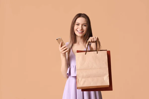 Jonge Vrouw Met Mobiele Telefoon Boodschappentassen Kleur Achtergrond — Stockfoto