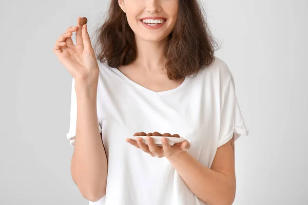Όμορφη Νεαρή Γυναίκα Τρώει Νόστιμες Καραμέλες Σοκολάτας Λευκό Φόντο — Φωτογραφία Αρχείου