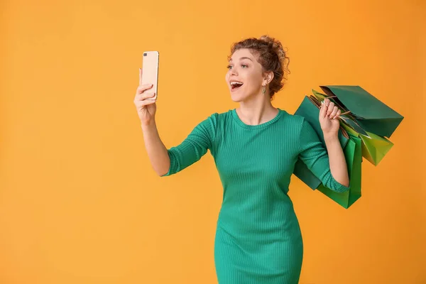 Mooie Jonge Vrouw Met Mobiele Telefoon Boodschappentassen Kleur Achtergrond — Stockfoto