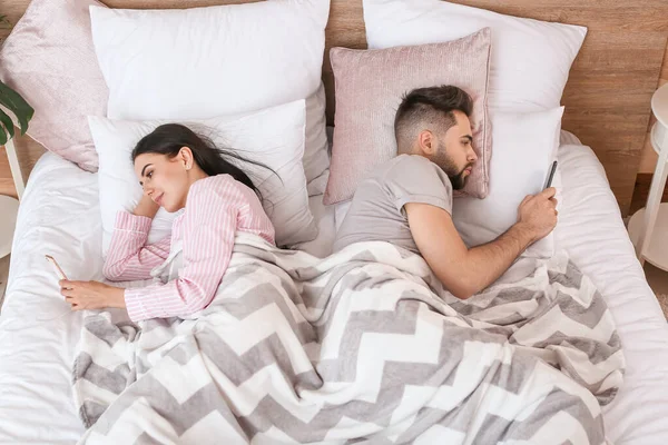 Unga Par Med Mobiltelefoner Liggande Sängen Hemma — Stockfoto