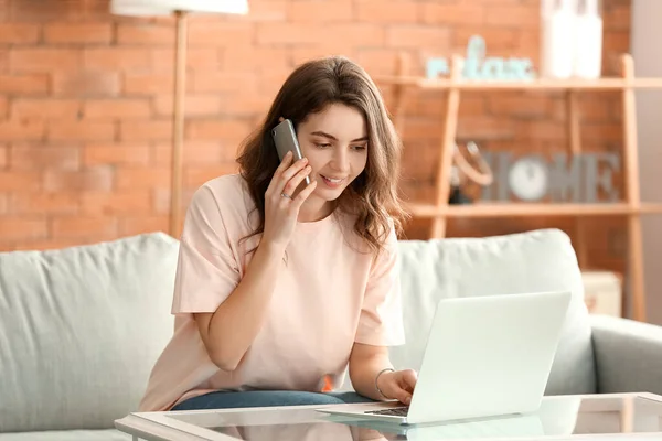 Красива Молода Дівчина Розмовляє Телефону Працюючи Ноутбуці Вдома — стокове фото