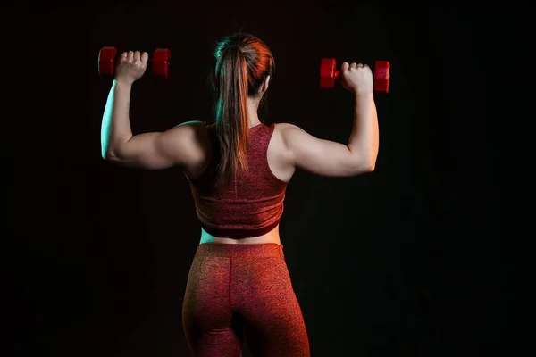 运动肌肉发达的女人与哑铃在黑暗的背景 — 图库照片