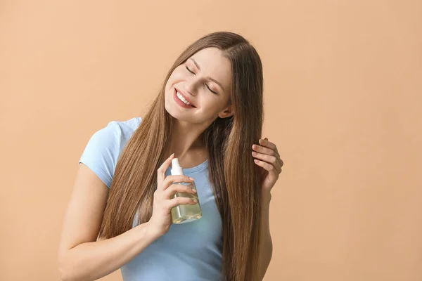 Beautiful young woman with hair spray on color background