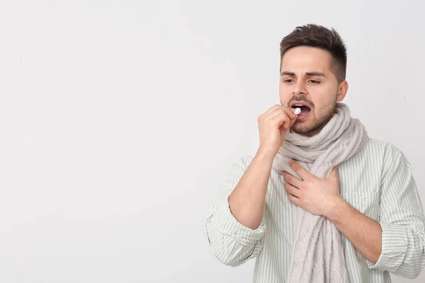 Ill Young Man Taking Pill Light Background — Stock Photo, Image