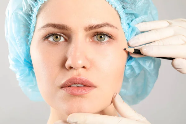 성형외과 의사가 배경에 여성의 얼굴에 칼자국을 붙이는 — 스톡 사진