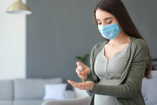 Pregnant woman using sanitizer at home. Concept of epidemic