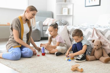 Dadı ve sevimli küçük çocuklar evde oynuyorlar.