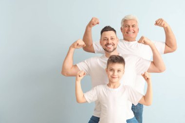 Babası ve oğluyla birlikte renkli arka planda kaslarını gösteren bir adam.