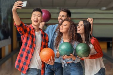 Arkadaşlar kulüpte bowling oynarken selfie çekiyorlar.