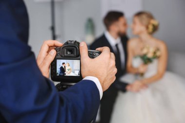 Stüdyoda genç bir çiftle çalışan fotoğrafçı, yakın plan.